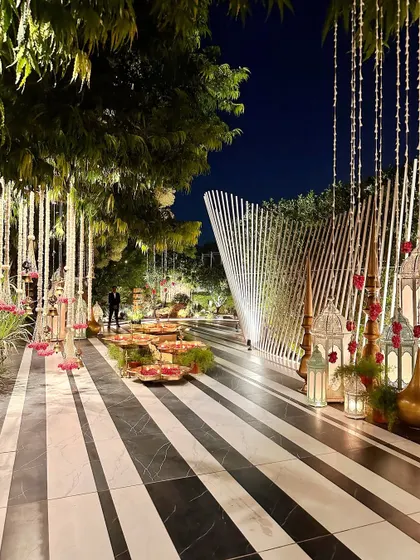 The grand entrance walkway at night, with its distinctive black and white striped flooring, lined with traditional decor, setting a magical tone for a wedding.