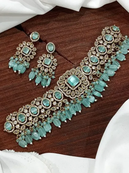 A versatile choker set available in multiple colors including white pearl, ruby, emerald, and pastel pink. The design features a central square motif with hanging beads, making it a popular choice for various festive occasions.