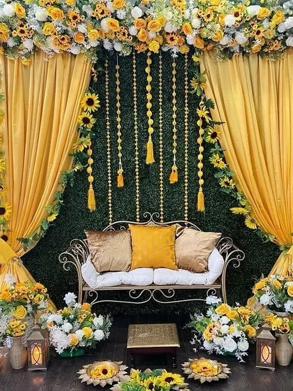 An elegant Haldi backdrop combining a green foliage wall with yellow drapes and an abundance of sunflowers, creating a fresh and vibrant look.