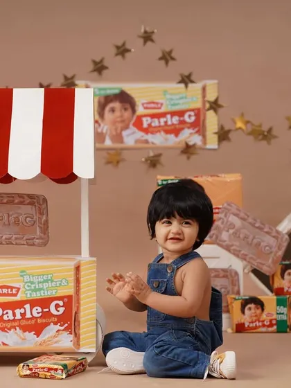 Capturing a moment of pure joy as the baby girl claps her hands during her Parle-G themed session.