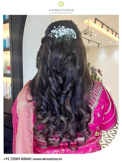 A beautiful half-up hairstyle with soft curls and fresh baby's breath, designed to perfectly complement a traditional saree for an elegant, feminine look.