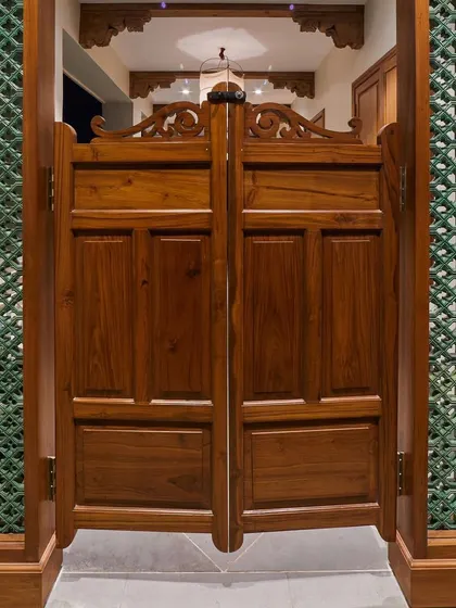 Inspired by my travels in Morocco, these wooden salon doors create a distinctive demarcation for a passage area. Paired with green ceramic *jali* on the sides, they allow for ventilation and create a beautiful play of shadows, bringing a touch of Moroccan style into the home.