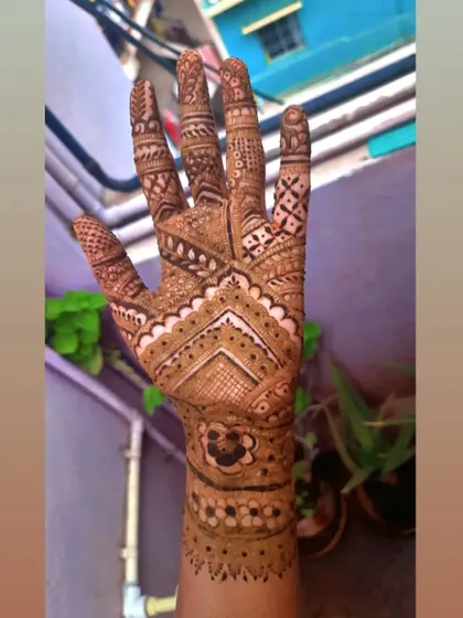 This design uses negative space to make the geometric patterns pop. The clean chevron lines on the back of the hand create a modern feel within a traditional bridal framework.