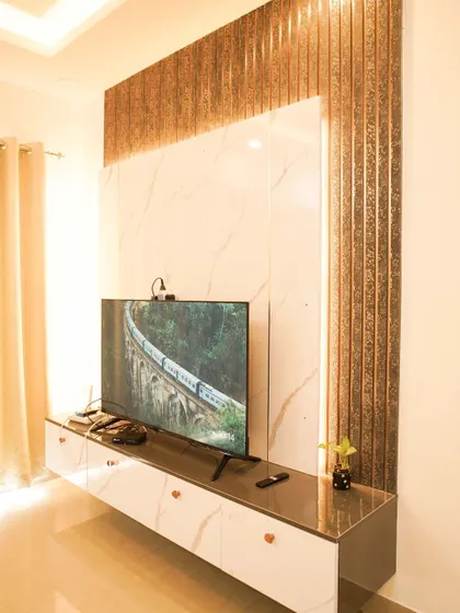 Another angle of the TV unit, showing the texture of the metallic fluted panels and the clean lines of the white marble. The design is modern, glamorous, and sophisticated.