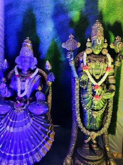 Statues of Lakshmi and Venkateshwara used as part of an event's decor, illuminated with dramatic blue lighting.