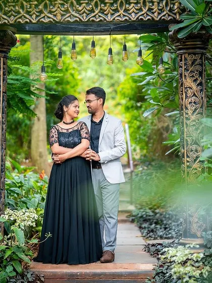 A full-length view of the couple in a garden walkway, framed by plants for a natural, intimate feel.