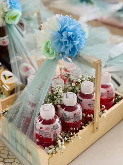 A handled pinewood tray filled with healthy drinks, perfect for an engagement or Haldi ceremony. The arrangement is decorated with baby's breath and a tulle bow.