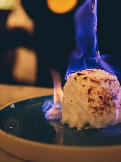 A close-up of a marshmallow dessert set ablaze, creating a caramelized crust.