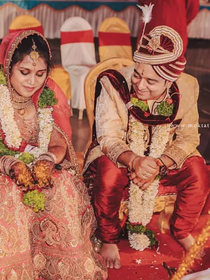 A candid moment from a Hindu wedding ceremony. The couple shares a quiet smile, seated at the mandap, surrounded by sacred traditions.