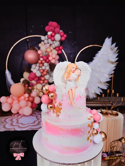 The beautiful, custom-made cake for the baptism, featuring a delicate angel and baby topper that perfectly matches the theme.