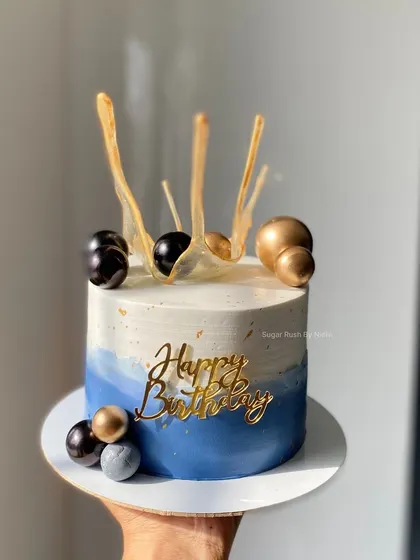 A modern blue and white cake with gold accents and isomalt spoon decorations. This design is perfect for a stylish and contemporary birthday celebration.