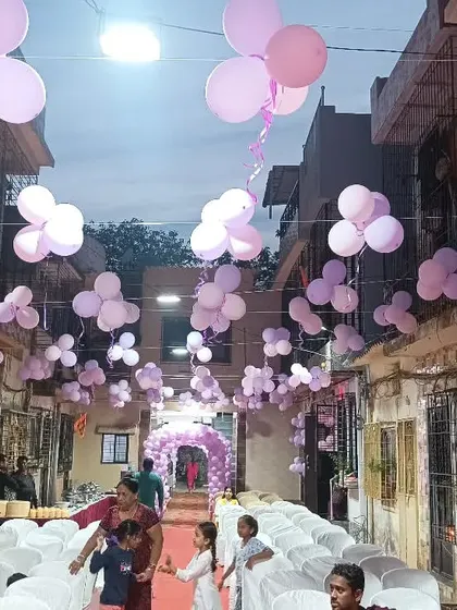 An outdoor venue decorated for a butterfly theme, with purple balloon bunches hanging overhead.