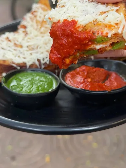 Dipping a piece of my Melting Sandwich into a spicy red sauce. It's a flavour explosion in every bite.