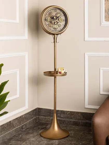 This elegant standing clock in a gold finish is designed for both style and function. It features a small tray perfect for holding keys or a cup of tea, and hooks for hanging small items, making it a great addition to an entryway.