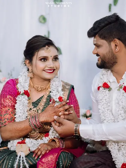 A sweet moment during the engagement ceremony as the groom holds the bride's hand. The focus is on their interaction and happy expressions.