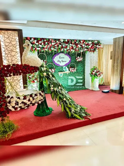 A wide shot of our floral peacock and cradle decoration. This view shows how the entire stage comes together with a green backdrop and floral valance for a cohesive and impressive look.