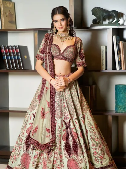Regally adorned in soft, stunning hues. This full-length shot showcases a breathtaking designer lehenga, paired with soft, glamorous makeup.