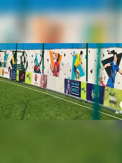 A wide view of the football-themed mural, showing how the artwork runs along the entire length of the turf. It creates an exciting and professional atmosphere for players.