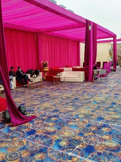 A dedicated lounge area inside a tent, featuring white sofas and center tables set against a vibrant pink backdrop.