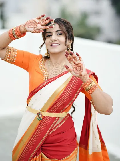 A playful and happy pose from Namratha Gowda, showing off her festive mehendi. The central mandala design on her palms is clearly visible and adds to the joyful mood.