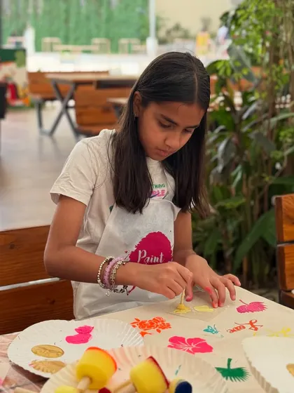 A young participant at a tote bag painting birthday party. The concentration and creativity are inspiring.