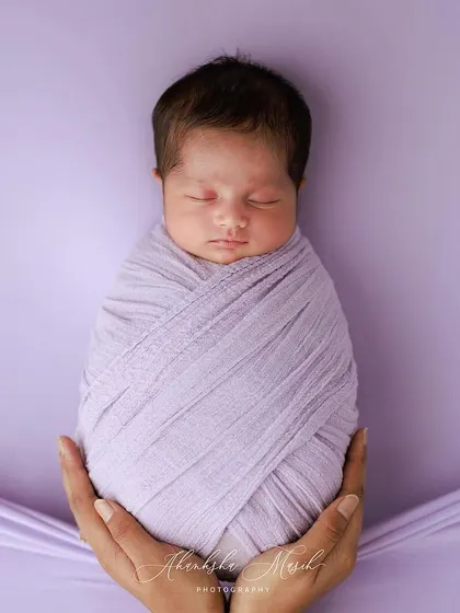 A duplicate image, this classic swaddle pose held in hands is a testament to the baby's tininess and the love that surrounds them.