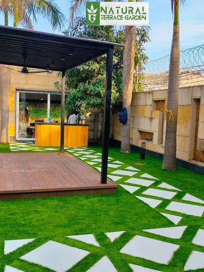 The completed landscape in Dwarka, showcasing the seamless integration of the lawn, pathway, and raised deck with pergola.