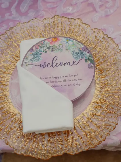 A personalized welcome card placed on a golden charger plate, showcasing the attention to detail that goes into my themed table settings.
