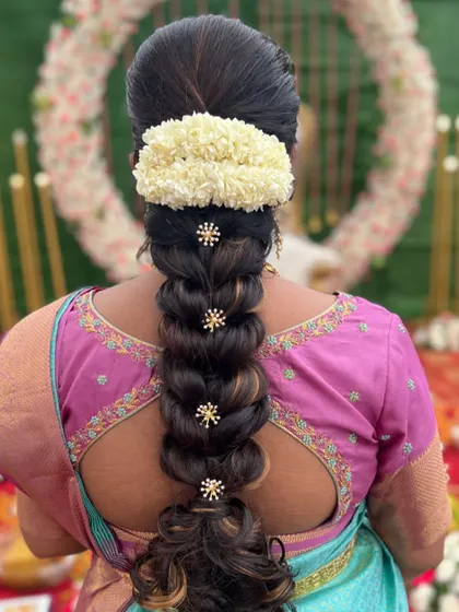 A beautiful bubble braid decorated with small, star-like floral accessories. This hairstyle adds a touch of modern elegance to a traditional silhouette.