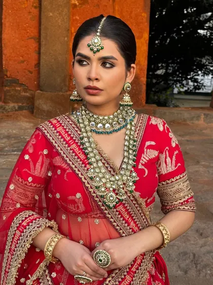 A soft glam look with shimmers of gold and brown, perfect for a North Indian wedding. The model looks radiant in a red lehenga with a nude lip.