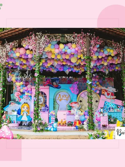 The main stage of the Alice in Wonderland party, featuring a ceiling of colorful balloons, character cutouts, and a magical keyhole entrance.