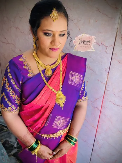 A traditional makeover for a housewarming event. The makeup features defined eyes and a bold lip to match her vibrant saree.