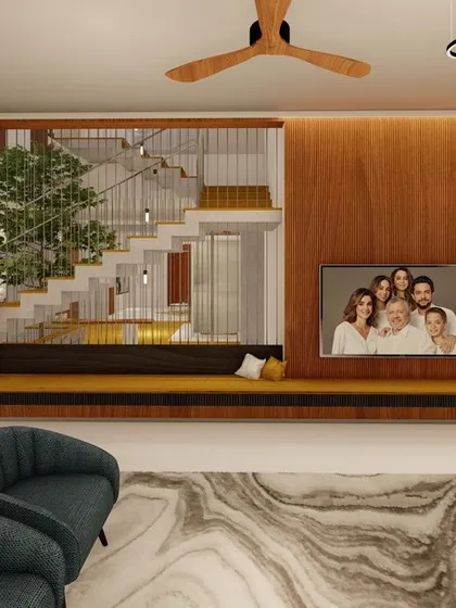 A family room featuring a warm wood-paneled wall that incorporates a TV and a long, built-in seating bench. In the background, a staircase wraps around an indoor courtyard, bringing nature into the heart of the room.