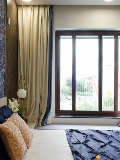 A master bedroom with a large bay window, providing ample natural light and a beautiful view. The color palette of beige and blue creates a calm and sophisticated retreat.