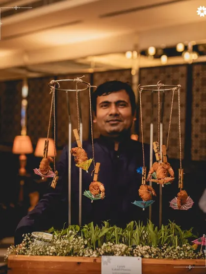 An innovative way to serve pass around appetisers. Here, crispy fried prawns are clipped to a hanging mobile, creating an interactive and whimsical presentation that delights guests.