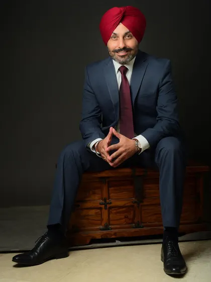 A full-length seated portrait of a professional in a suit and turban. Using props like this wooden chest in the studio adds character and a unique element to the shot.