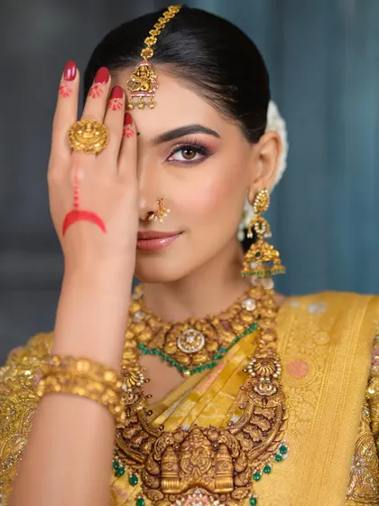 A unique and artistic pose, with the bride's hand partially covering her face. This draws attention to the traditional hand decoration and the intense, beautiful eye makeup.