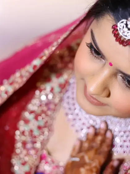 A high-angle close-up of the bride, focusing on her makeup and the delicate details of her jewelry.