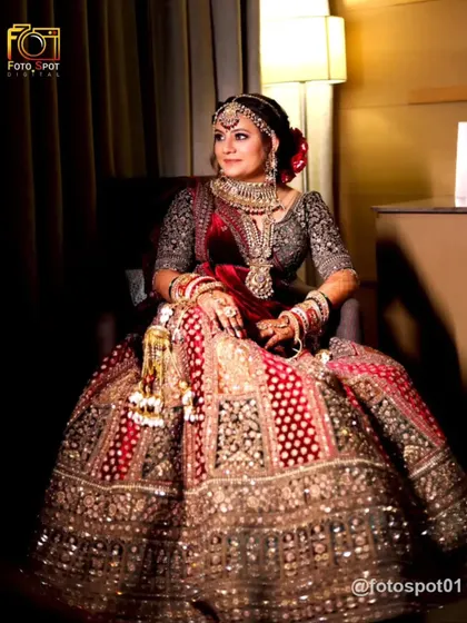 A full-length portrait of the bride seated, showing off the grandeur of her heavily embroidered lehenga. The warm lighting creates a classic, elegant mood.