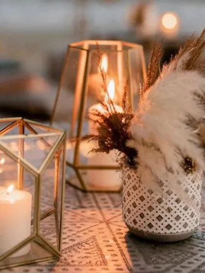 A close-up of the cozy details that make a space feel special. This image shows geometric candle holders and a vase of pampas grass, creating a warm and inviting corner on the dinner table.