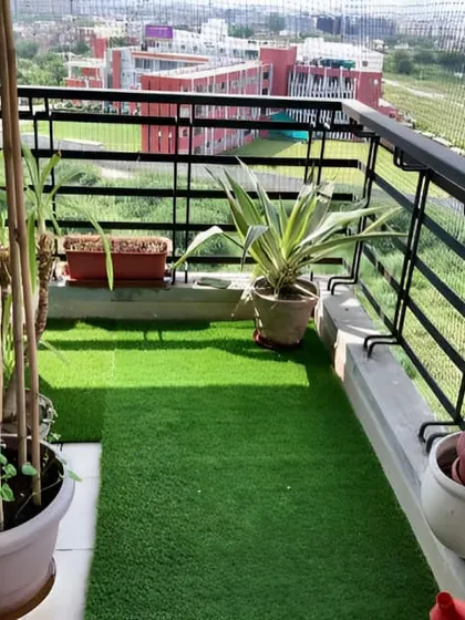 A practical and low-maintenance balcony setup. The use of artificial turf provides a soft, green base, while a few potted plants and a safety net make it a simple and usable outdoor area.