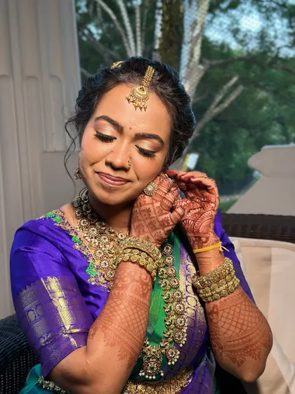 A moment of quiet reflection before the ceremony. I used soft gold tones on the eyes to complement her traditional temple jewellery and royal blue Kanjeevaram saree, creating a look of pure grace.