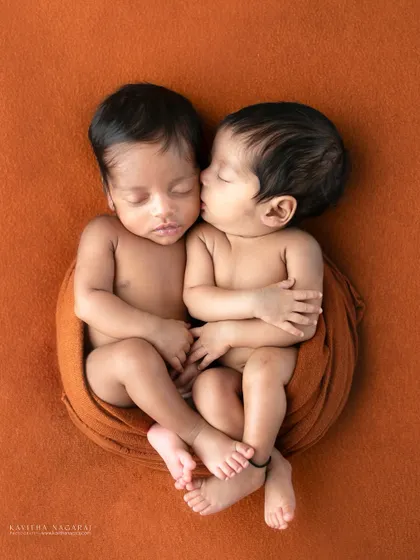 A beautiful portrait of newborn twins, with one giving the other a gentle kiss on the cheek. This image perfectly captures the pure magic and love of their bond.
