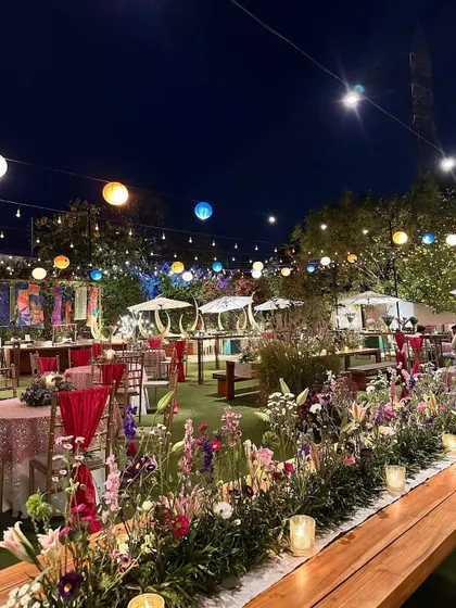 A long view of a colorful evening event, with a mix of seating arrangements and bright floral runners.
