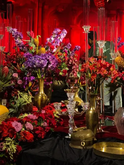 A lush corner of the Siddartha Tytler set, showcasing a rich mix of purple, red, and orange blooms in brass vases. This layering of color and texture is a signature of my maximalist designs.