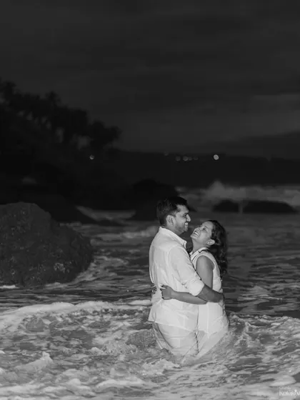 A black and white photo of a couple embracing in the ocean at night. This timeless image focuses purely on their connection and the texture of the water around them.