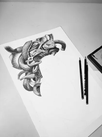 Another angle of the Medusa work-in-progress. This minimalist shot focuses on the completed section, highlighting the contrast and detail against the blank paper.