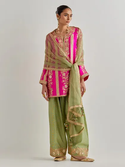 The full view of the fuchsia and olive green ensemble. The wide-legged pants are also embroidered at the hem, showing attention to detail throughout the entire outfit.