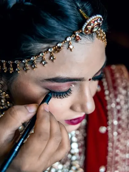 A close-up shot of the makeup artist applying eyeliner, highlighting the precision and artistry involved in creating the perfect bridal look.