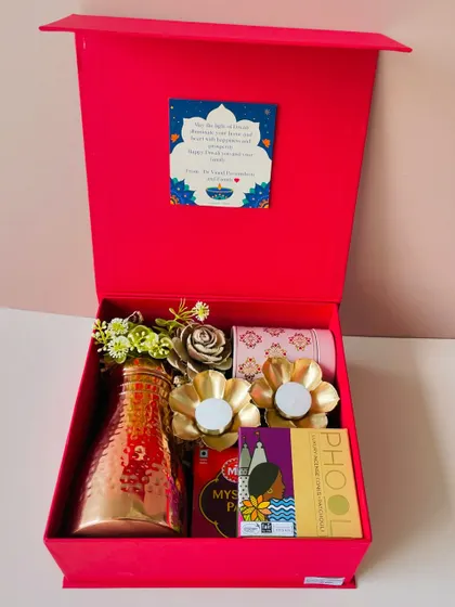 Our vibrant red gift box with a magnetic flap closure. This one is curated with a hammered copper bottle, flower-shaped diyas, and luxury incense.